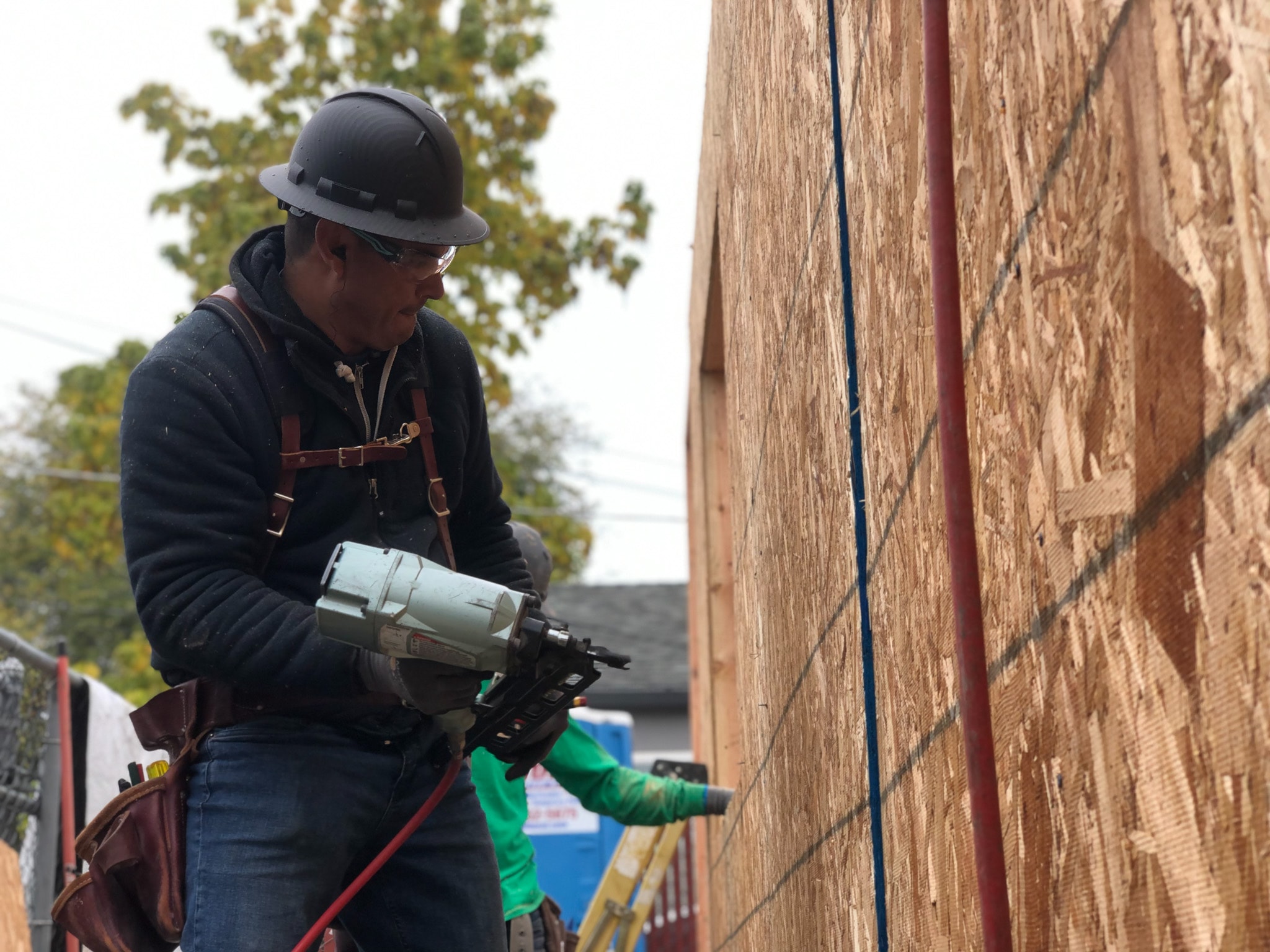 Crew member using nail gun on wall